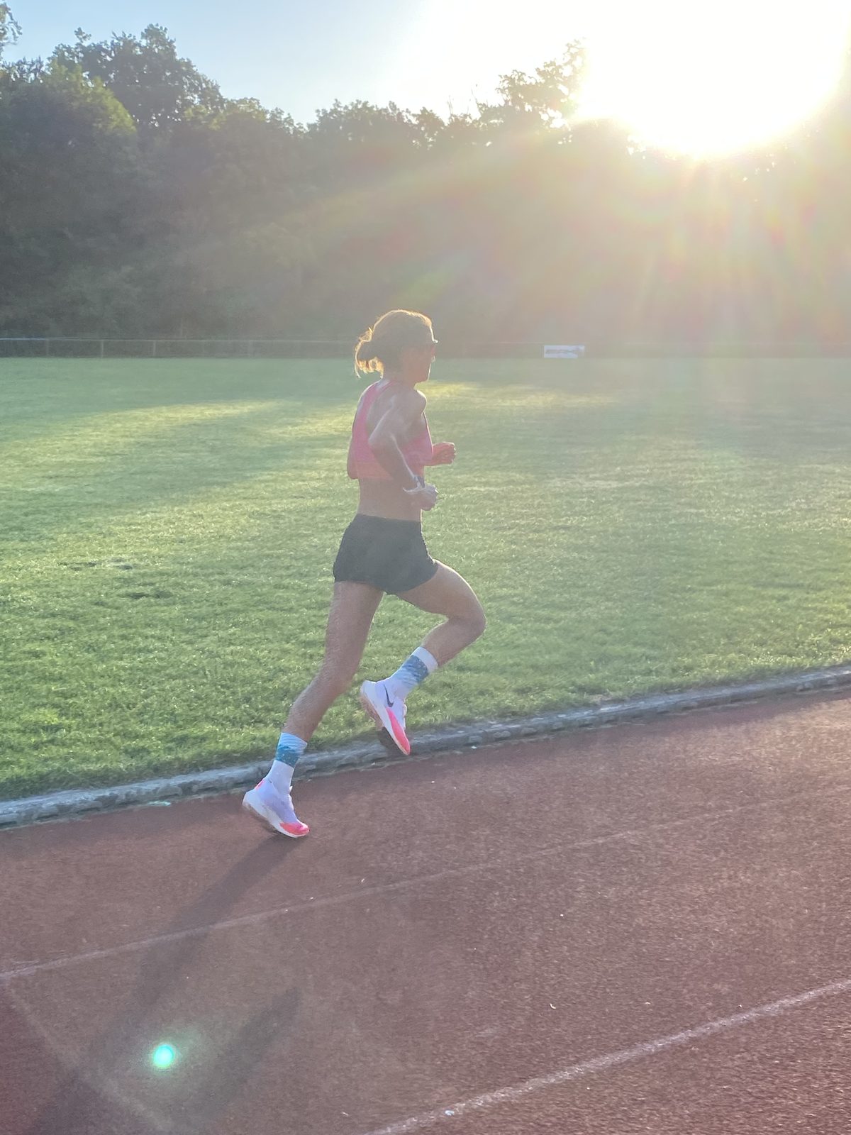 Nici läuft im Gegenlicht der Morgensonne allein auf einer Laufbahn