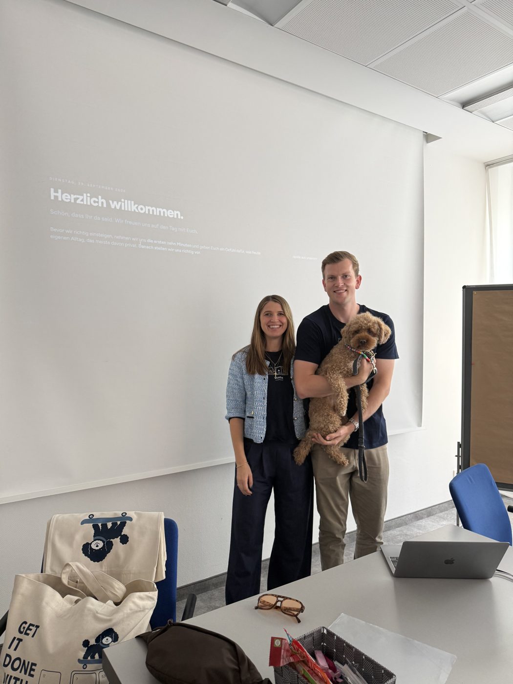 Carina und Luca mit Hund Carlo vor der Begrüßungsfolie im Seminarraum